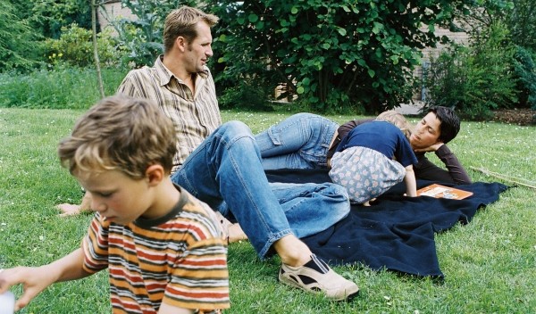 Familie die im Garten auf einer Wolldecke liegt