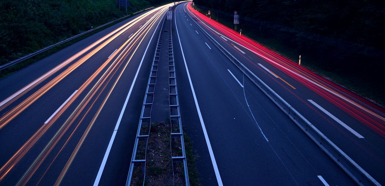 Autobahn bei Nacht. Man sieht keine Autos sondern nur Lichtstrahlen