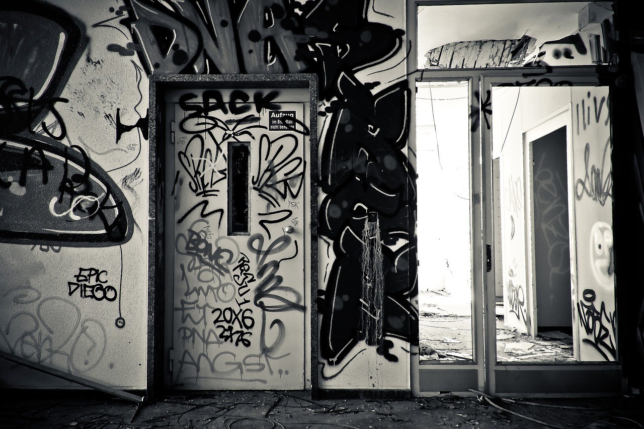 Schwarzweiß-Foto. Ein Aufzug in einem Treppenhaus, voll beschmiert mit Graffitti