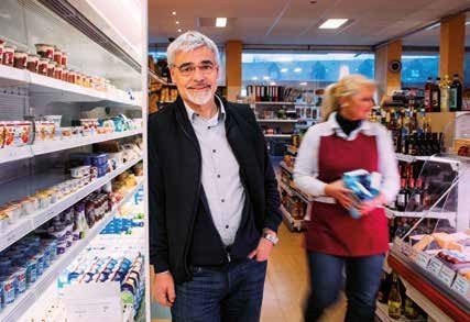 Heinz Freiy lehnt sich lächeln an eine Kühltheke im Dorfladen